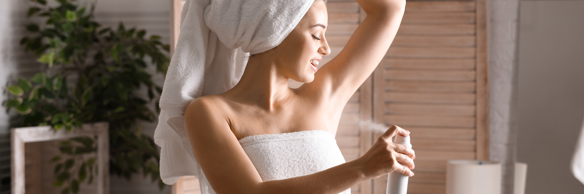 Beautiful young woman applying deodorant after shower in bathroo